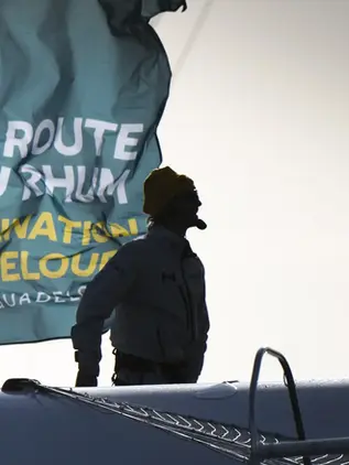 A skipper in front of the Route du Rhum flag